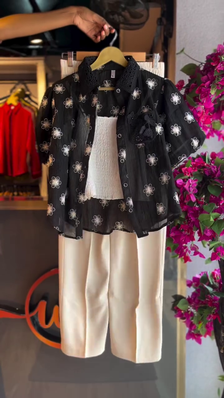 “Chic & Contemporary: Black Embroidered Floral Shirt with White Top and Cream Trousers”